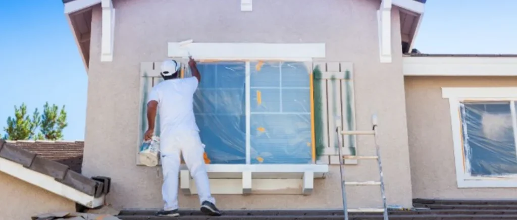 worker painting the exterior of a home