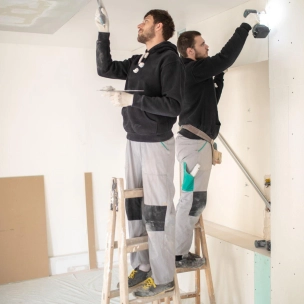 men on ladders repair drywall